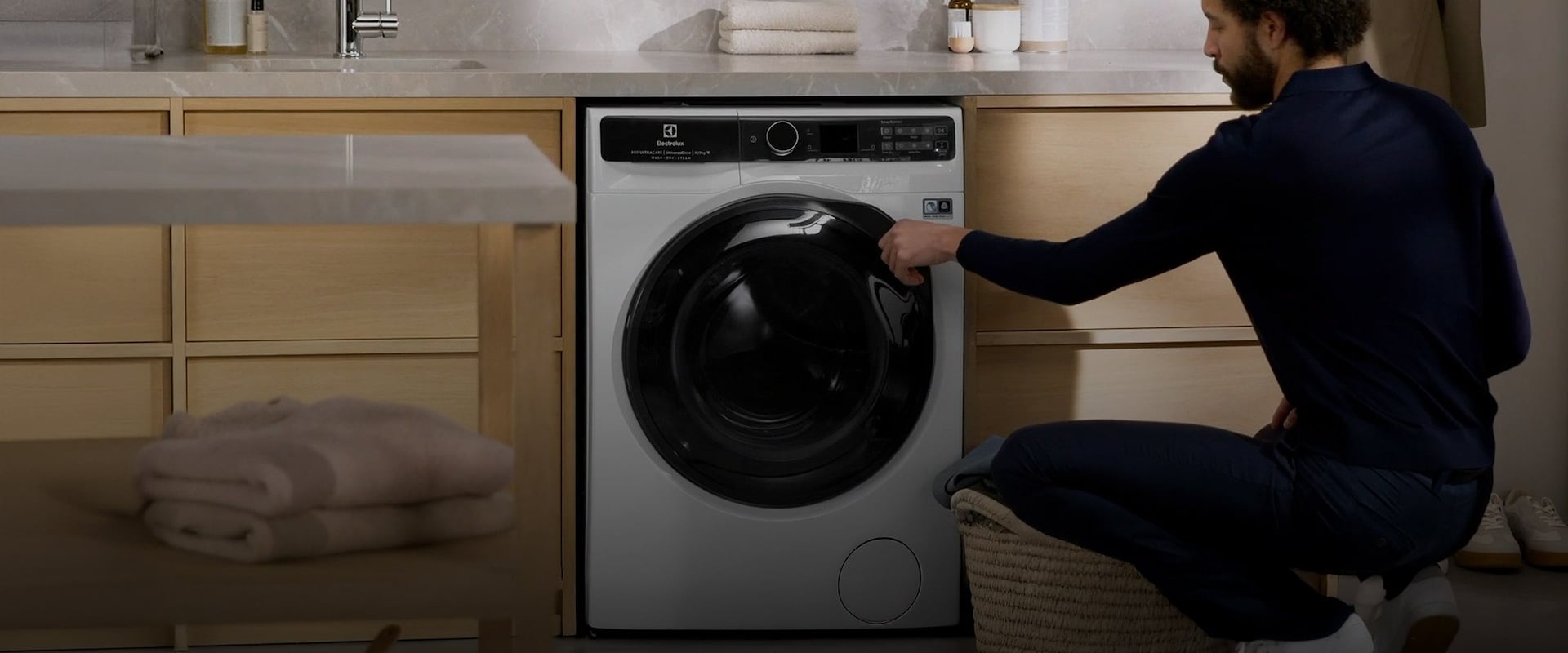 En mand lukker lågen på en vaskemaskine.